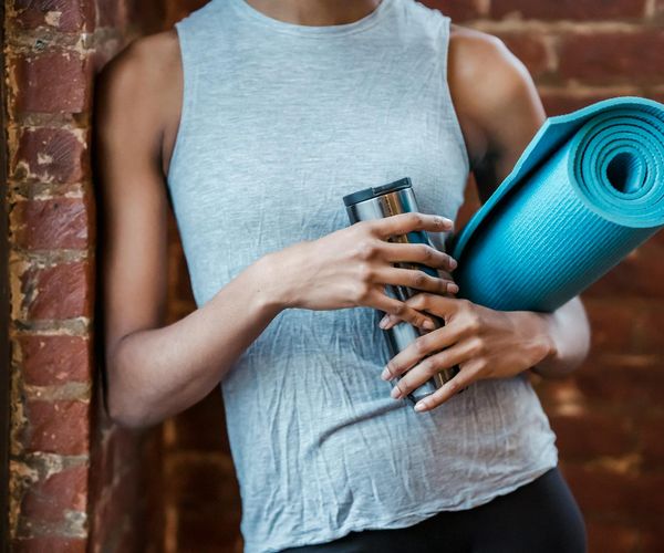A water bottle and a small towel next to rolled up exercise mat.